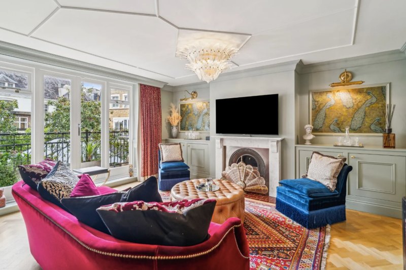 A drawing room with a velvet sofa and fireplace